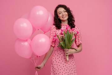 pretty young woman posing isolated on pink studio background with tulips flowers