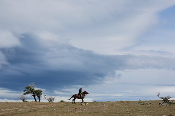 Man riding a horse on top of a cliff in an isolated area