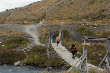 Hikers crossing a wooden bridge in Torres del Paine National Park in Chilean Patagonia