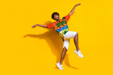 Fototapeta na wymiar Full size photo of optimistic man dressed print shirt white shorts dancing hold palms like wings isolated on yellow color background