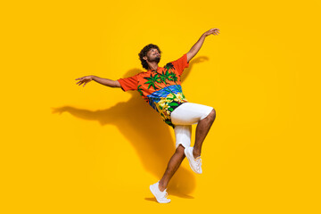 Fototapeta na wymiar Full size photo of funky man dressed print shirt white shorts dancing look up at promo empty space isolated on yellow color background