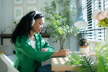 Young woman with headphones listening to music while sitting at table in room