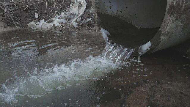 Dirty water flows from the pipe into the river, environmental pollution