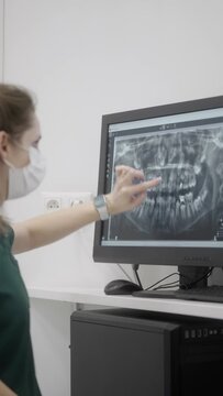 An orthodontist intern performs an examination and shows the structure of the teeth on an X-ray. Obtaining medical education and advanced training. A dentist diagnoses a dental disease.