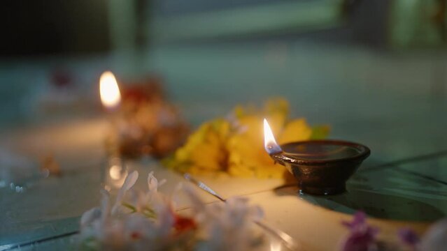 Candle flames flicker among vibrant flower offerings on temple altar at night. Sacred ritual, serene Buddhist worship scene with incense. Traditional spiritual practice in Asia, devotion ambiance.