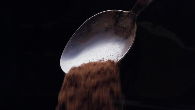 Slow motion spoon cocoa powder falling against balck background