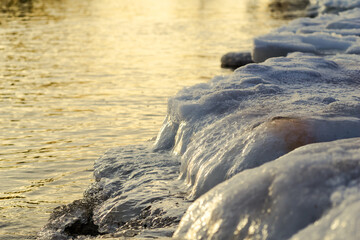 small waves of the Baltic Sea pour over the icy shore in winter