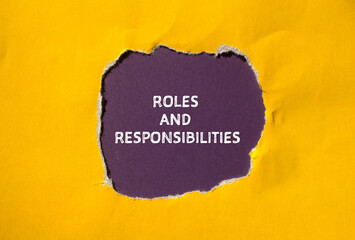 Roles and responsibilities words written on torn yellow paper with purple background. Conceptual...