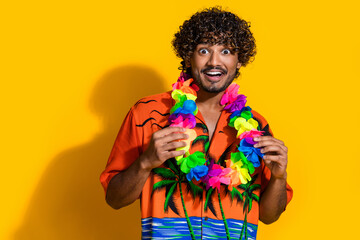 Photo of ecstatic man with afro hair dressed print shirt holding flower necklace astonished staring...