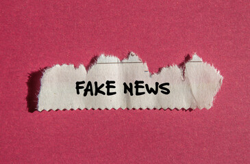 Fake news words written on white torn newspaper piece with red background. Conceptual symbol. Copy...