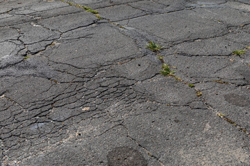 Extremely decayed street asphalt surface with cracking and crumbling, creative copy space,...