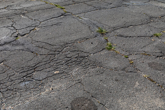 Extremely decayed street asphalt surface with cracking and crumbling, creative copy space, horizontal aspect