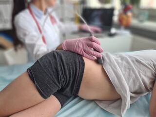 Doctor conducting ultrasound examination of kidneys to child in clinic. 