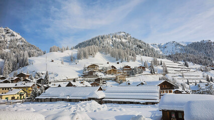 Beautiful winter view of village Arabba in Italy, province Belluno, after heavy snowfall. Slightly blue sky with snow covered houses, trees and mountains. 