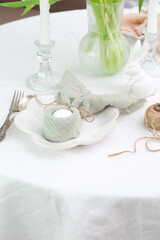 Beautiful table serving for Easter celebration in dining room, plate with easter egg and bunny, vase with flowers. Easter table setting.