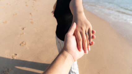 A couple holding hands at beach.Engaged couple touching hands on the beach - romantic scene