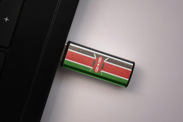 usb flash drive in notebook computer with the national flag of kenya on gray background.