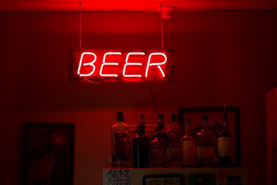 bar counter in a bar, neon beer sign, red bright neons - Powered by Adobe