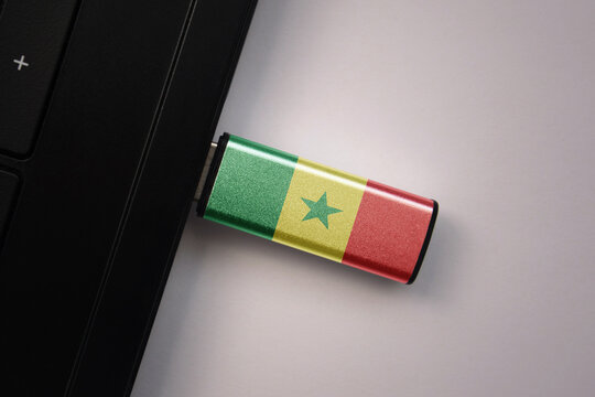 usb flash drive in notebook computer with the national flag of senegal on gray background.