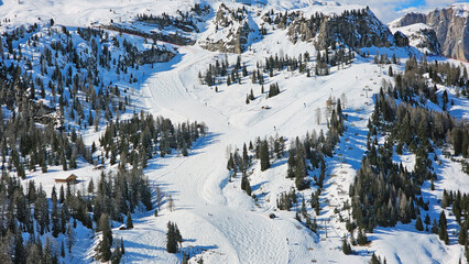 Ski resort from above on a sunny day. Skiing between the trees high in the Dolomites Mountains, Italy, South Tyrol. Beautiful bird view from Dolomiti Superski area.