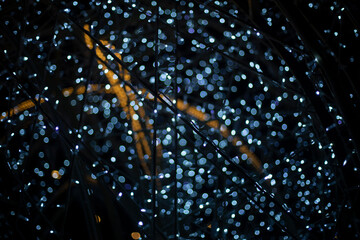 Garlands in dark. Bright light bulbs on black background. Decorating city during holidays.