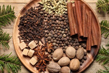 Different spices, nuts and fir branches on wooden table, flat lay