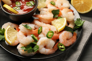 Tasty boiled shrimps with cocktail sauce, chili, parsley and lemon on table, closeup