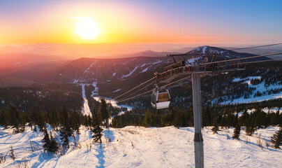 Aerial top view landscape ski lift resort with snowy forest on mountain in winter sunlight,...