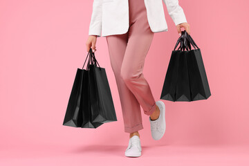 Woman with shopping bags on pink background, closeup