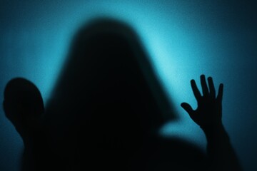 Silhouette of ghost behind glass against blue background