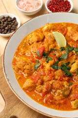 Delicious chicken curry and spices on table