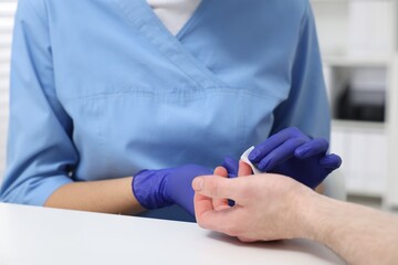 Laboratory testing. Doctor taking blood sample from patient at white table in hospital, closeup