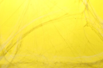 Creepy white cobweb hanging on yellow background