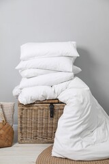 Soft pillows, duvet, bag and wicker trunk indoors