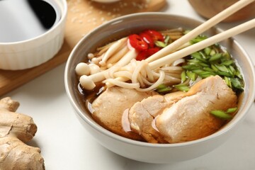 Delicious ramen with meat and ingredients on white marble table, closeup. Noodle soup