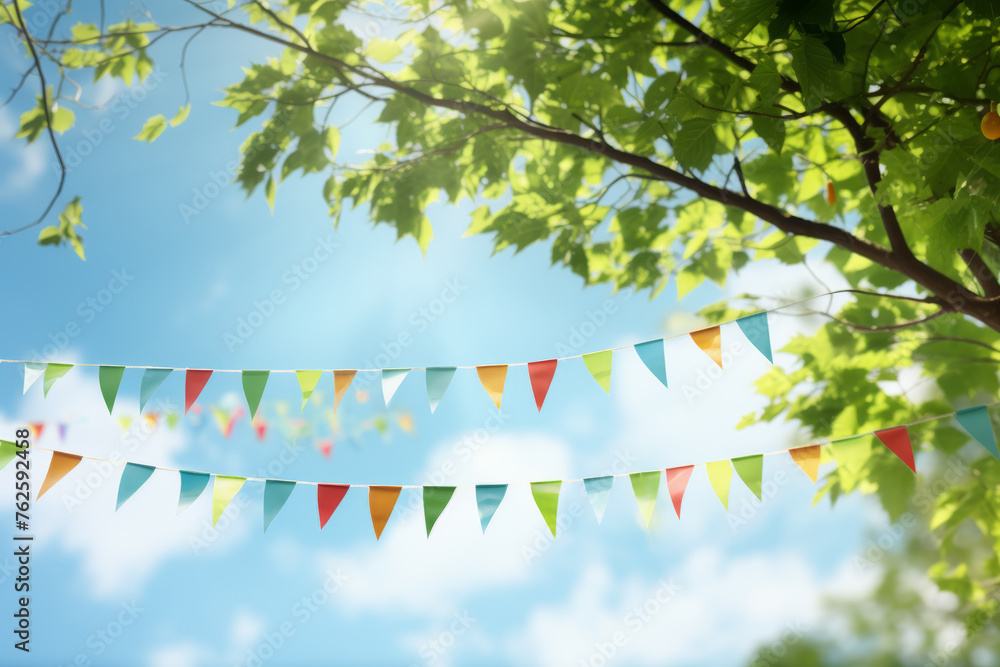 Poster bunch of colorful flags hanging from tree on sunny day. flags are of different colors and sizes, cre
