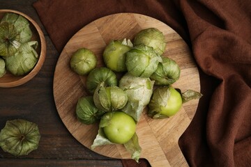 Fresh green tomatillos with husk on wooden table, flat lay
