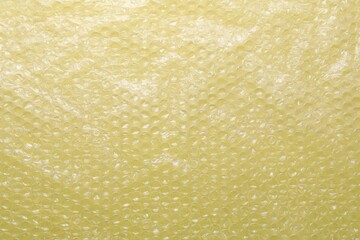 Transparent bubble wrap on yellow background, top view
