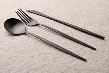Stylish cutlery set on beige textured table, closeup