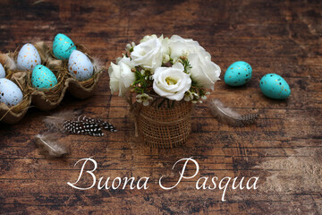 Biglietto d'auguri Buona Pasqua. Saluto pasquale con bouquet di fiori e uova di Pasqua su tavolo in legno rustico.