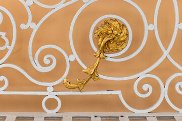 Vintage white forged railings with goldern flower in front of yellow wall