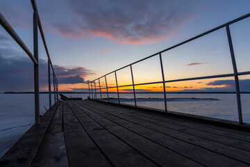 Abandoned broken pier is under sunset sky on a winter evening - obrazy, fototapety, plakaty