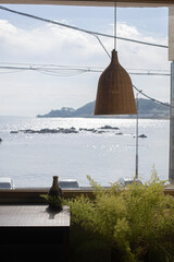 Rattan pendant lights over wooden table with ocean view