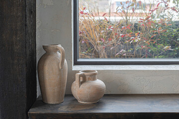 Two vintage ceramic vases in front of the window