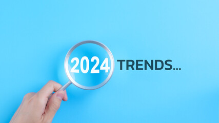 Trends 2024 year concept. Hand holding magnifying glass with 2024 trend searching bar for optimization 2024 business marketing trends and business plan in new year. Find information and new ideas. - obrazy, fototapety, plakaty