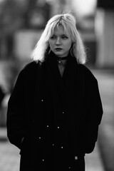 Portrait of a young beautiful blonde girl in a black coat. Black and white photo.