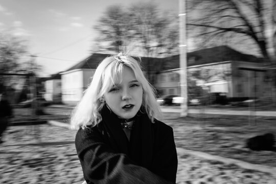 Portrait of a young beautiful blonde girl in a black coat. Black and white photo.