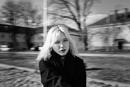 Portrait of a young beautiful blonde girl in a black coat. Black and white photo.