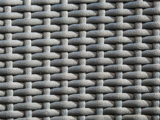 Close-up shot of the grey plastic rattan weaving of a outdoor furniture in sunlight