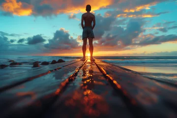 Papier Peint photo Descente vers la plage A person doing calisthenics exercises on a beach boardwalk at sunrise. Man gazes at ocean from pier at sunset, surrounded by water, sky, and afterglow